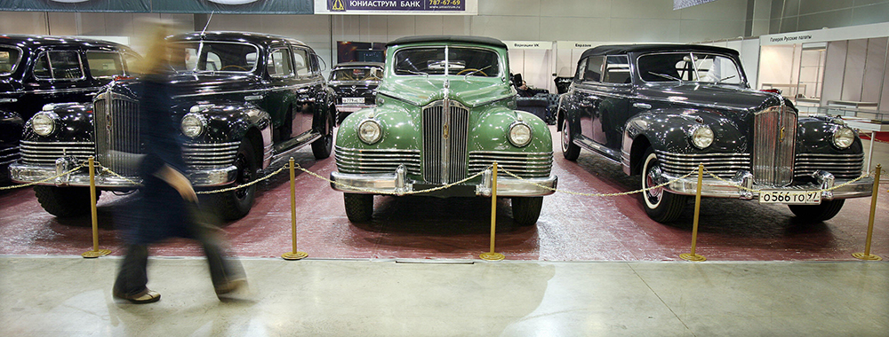 A woman  passes by ZIS-110 limousines us