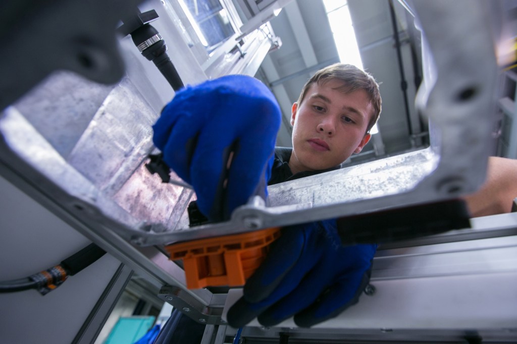 An employee attaches an electrical power socket to the aluminium casing of a lithium-ion battery at the Bayerische Motoren Werke AG (BMW) automobile manufacturing plant in Dingolfing, Germany, on Thursday, Aug. 21, 2014.