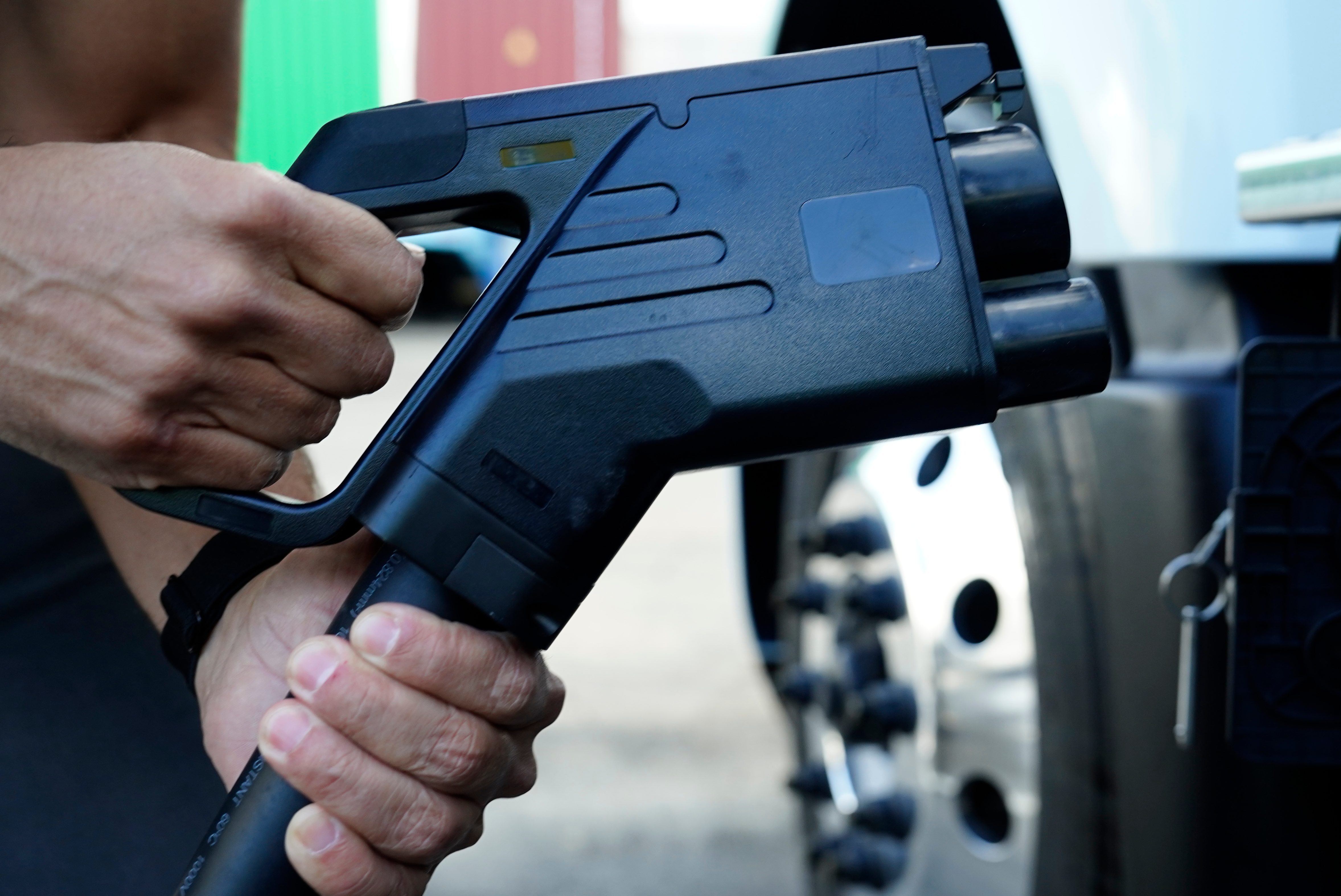 An executive demonstrates how to plug a CCS charger into a Volvo VNR electric truck at Hight Logistics in Long Beach, California, US, on Monday, Dec. 5, 2022. Forum Mobility replaces diesel drayage freight trucks, a major source of toxic emissions, with electric models for a monthly fee. Photographer: Bing Guan/Bloomberg via Getty Images